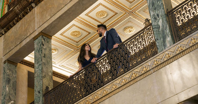 Vidhi and Mayank looking down from an ornate balcony