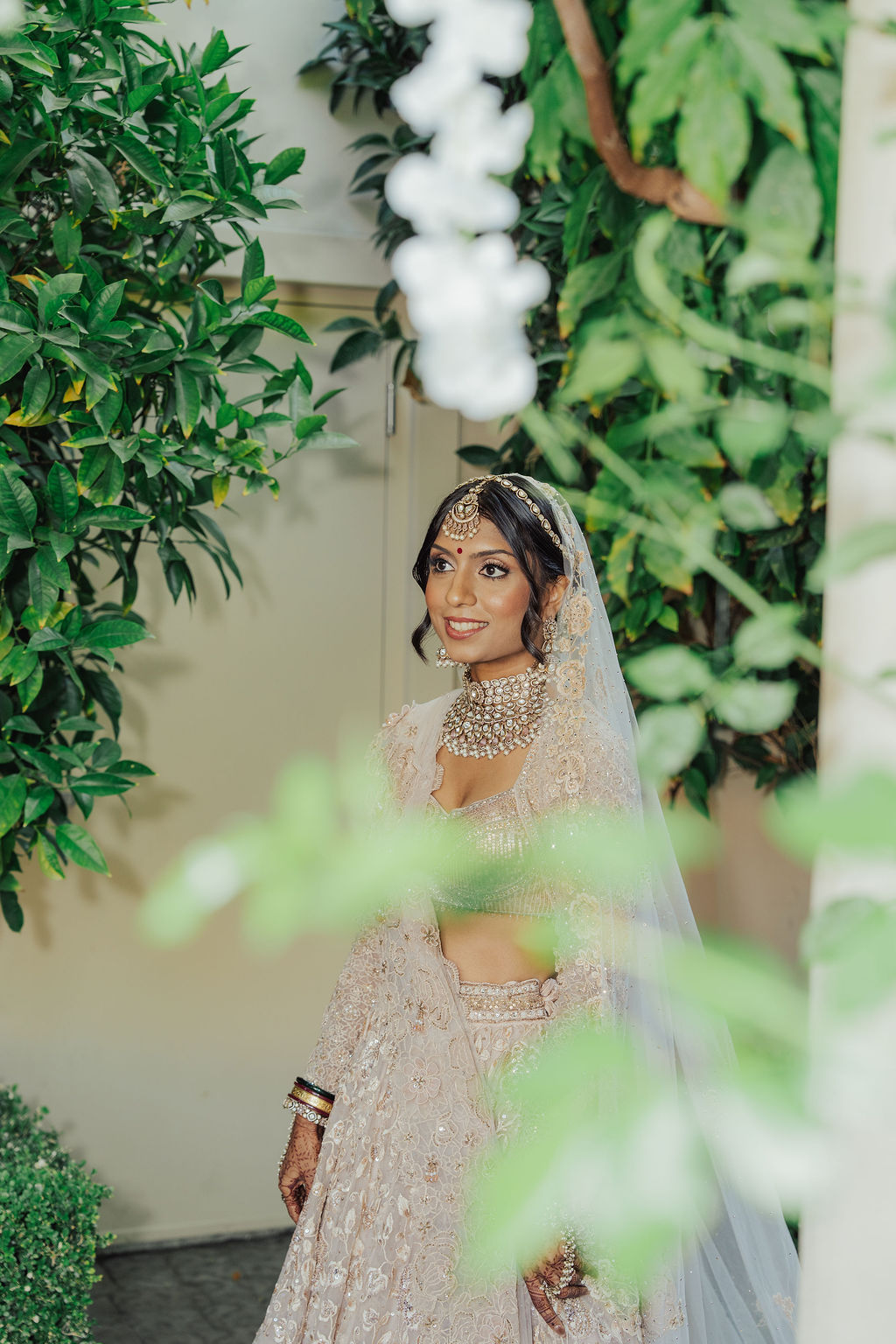Zohal in her ivory bridal veil among garden greenery